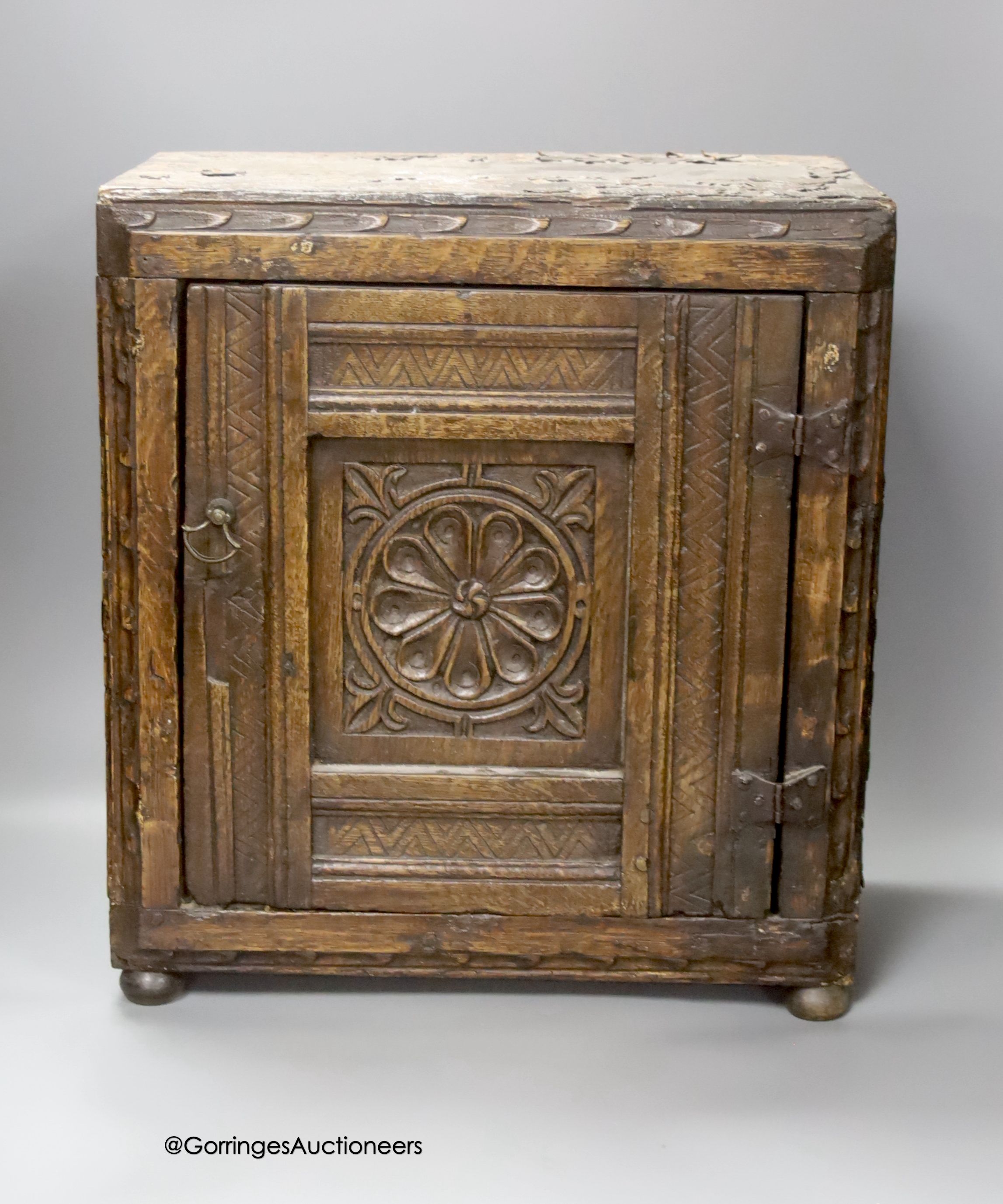 A small 17th century carved oak wall cabinet, enclosed by single panelled door with iron butterfly hinges, width 37cm